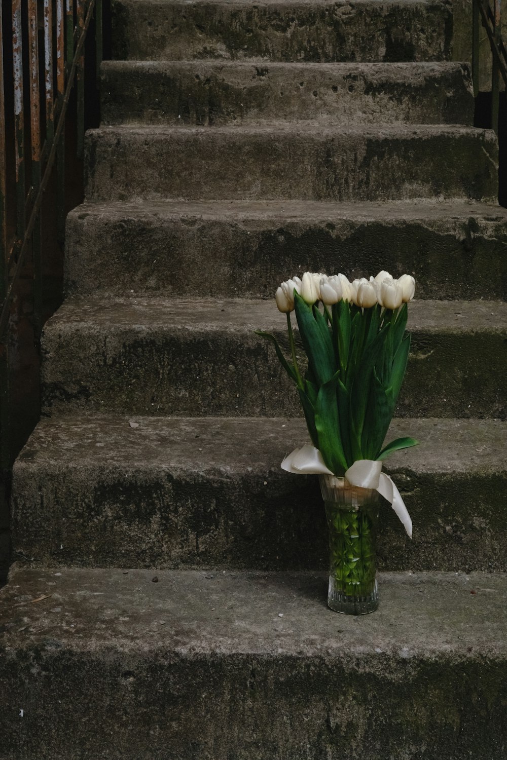 un bouquet de tulipes blanches assis sur un escalier