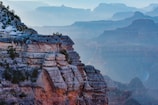 Wide shot of layered canyon landscapes with soft gray mist in the distance.