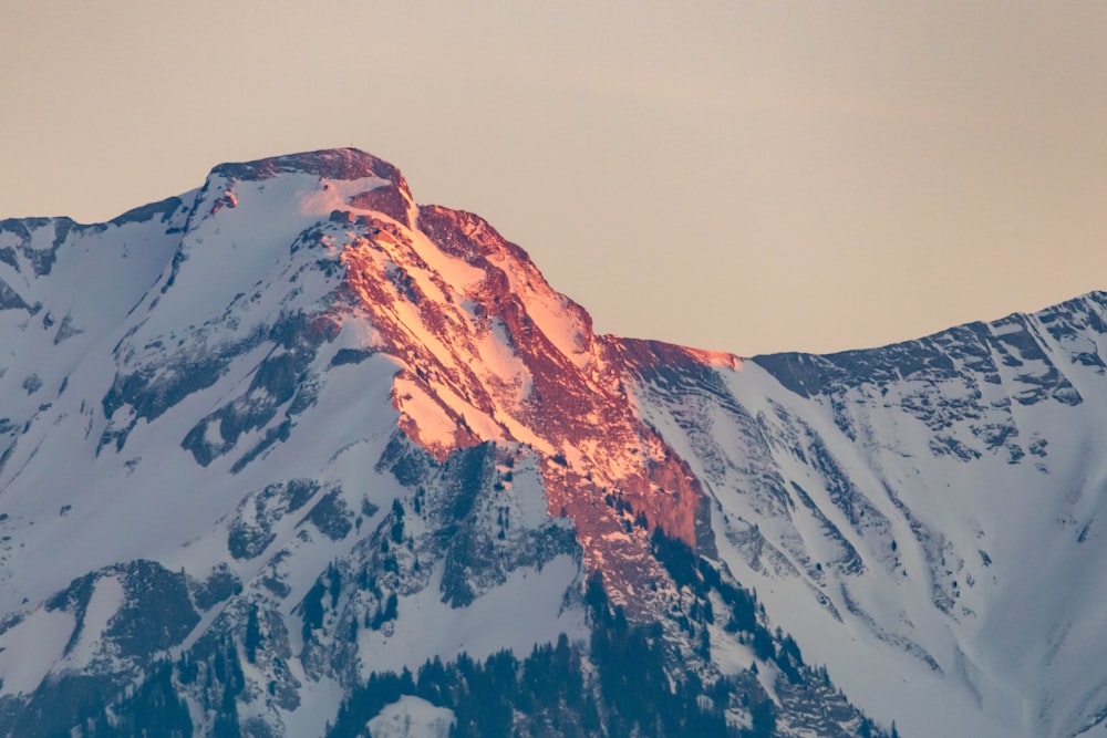 a large mountain covered in snow under a cloudy sky