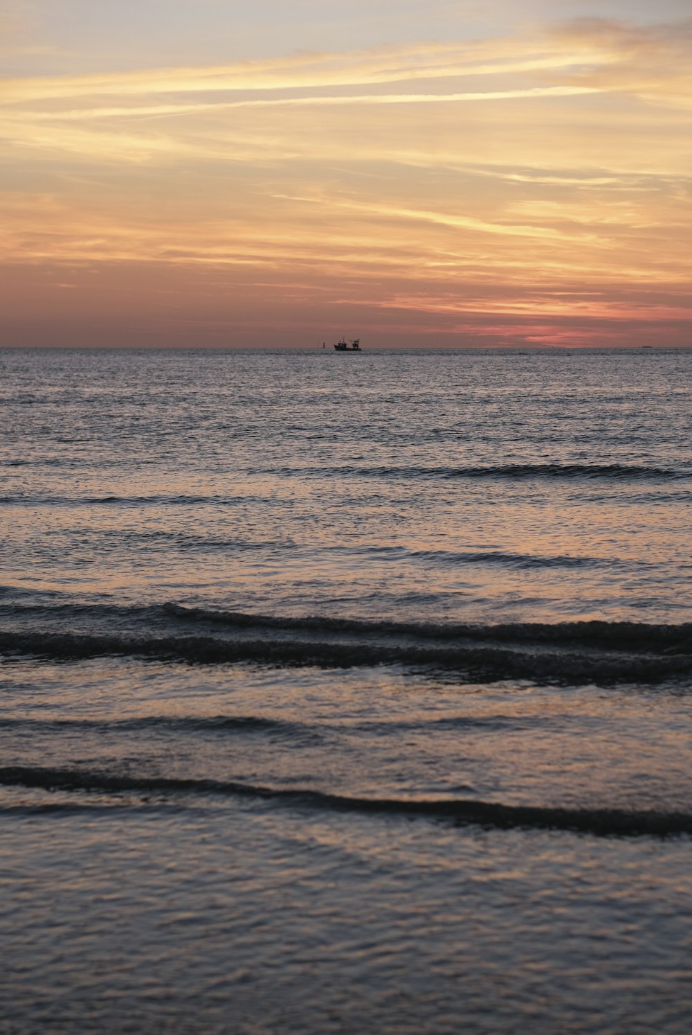 a couple of boats floating in the ocean at sunset