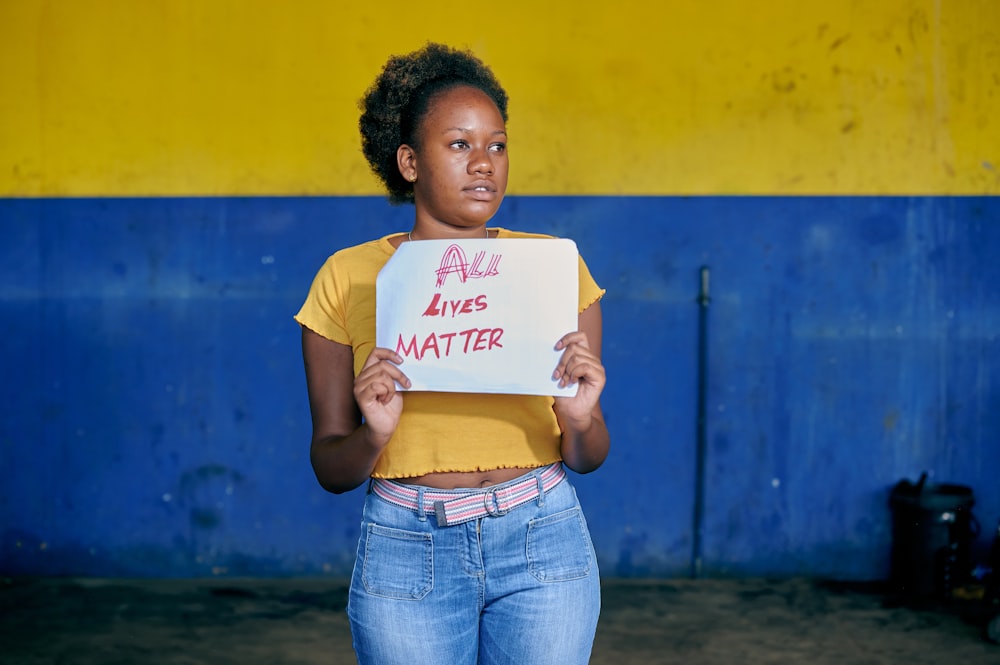 a woman holding a sign that says all aries matter