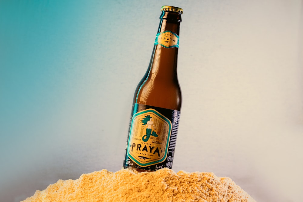 a bottle of beer sitting on top of a pile of sand