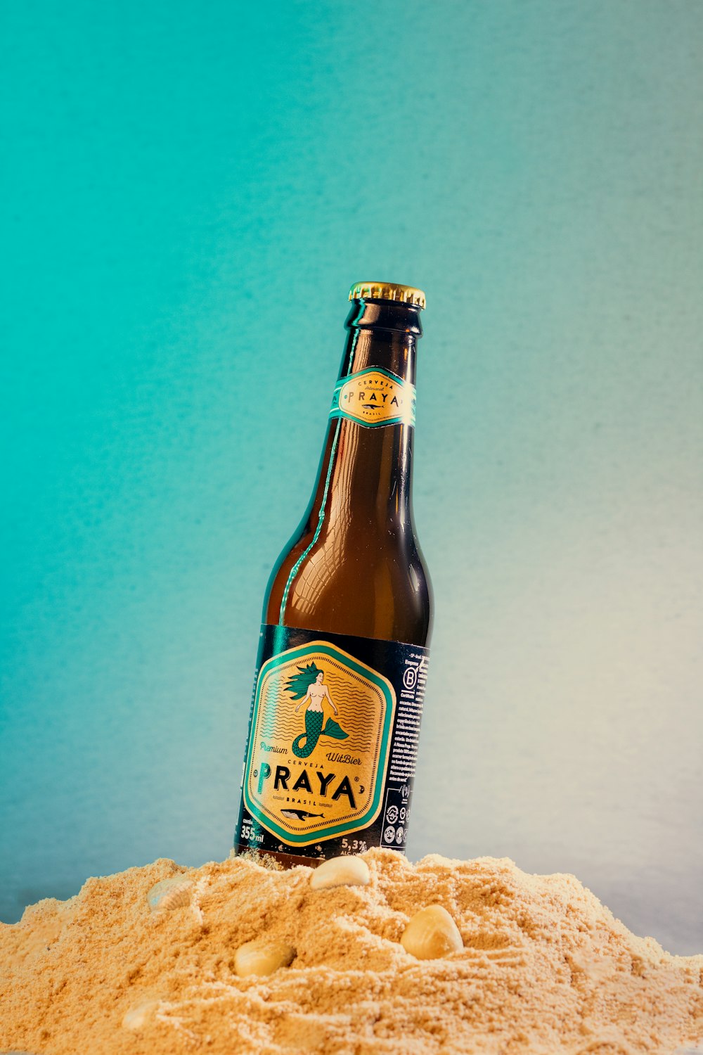 a bottle of beer sitting on top of a pile of sand