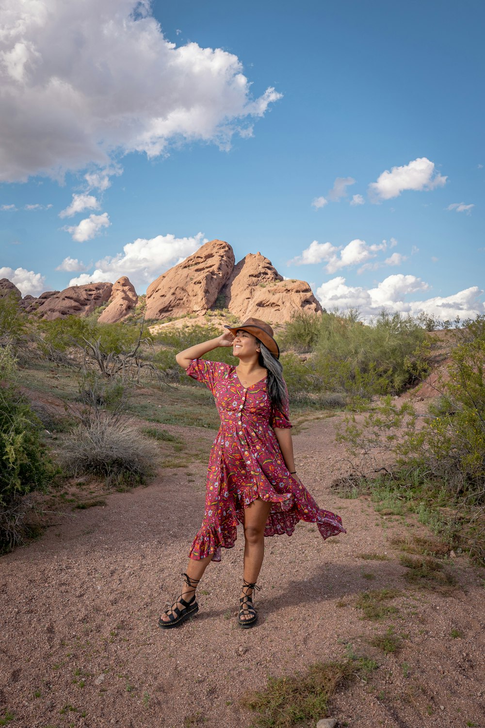 a woman in a dress and hat standing in the desert