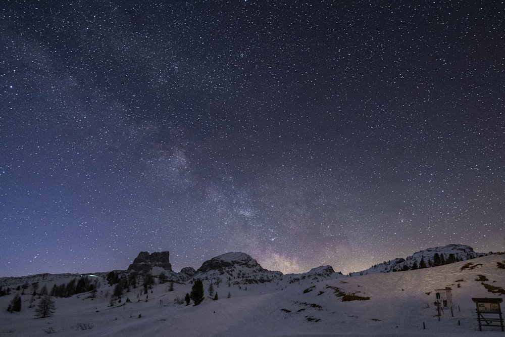 the night sky with stars above a snowy mountain