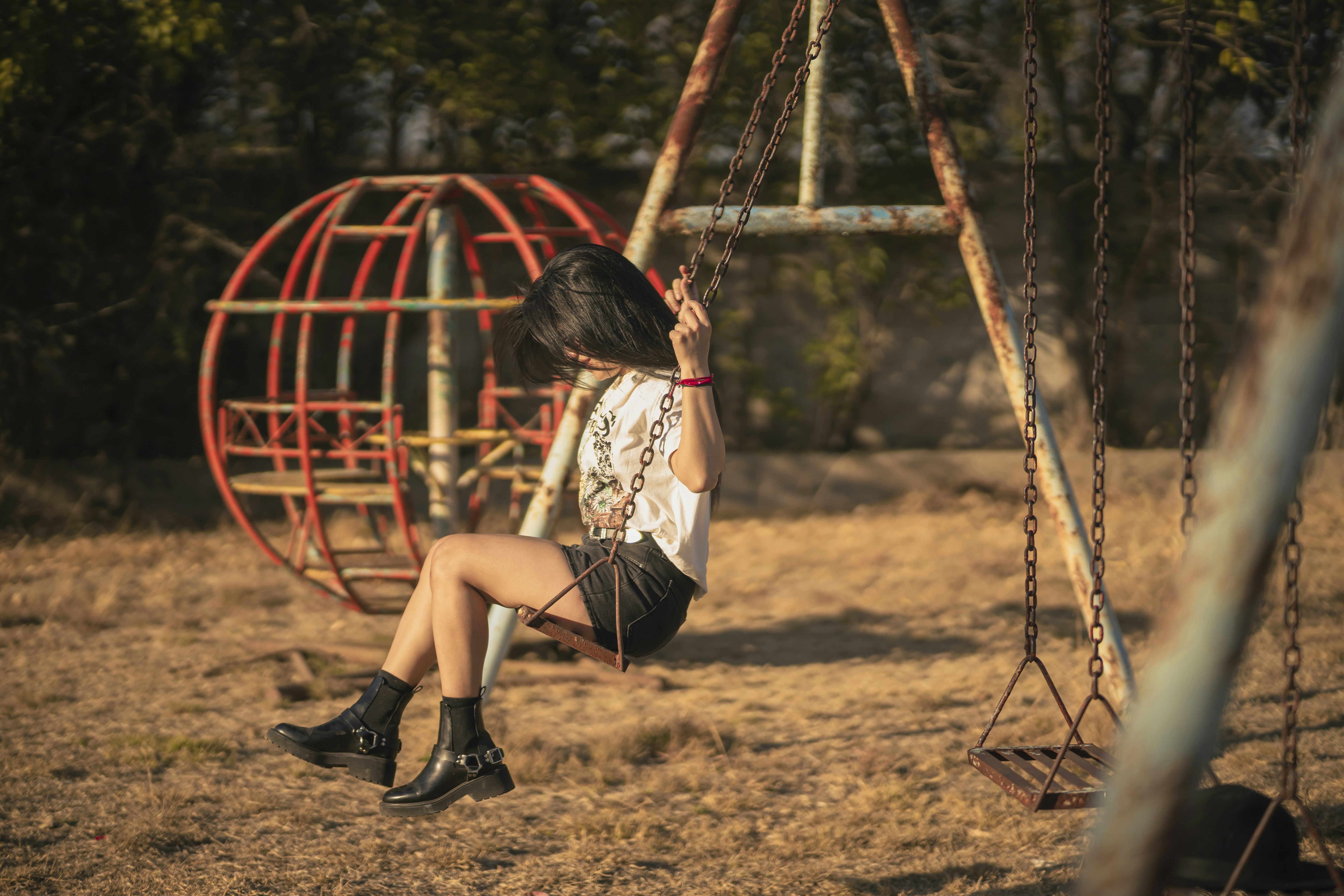 a woman sitting on a swing in a park