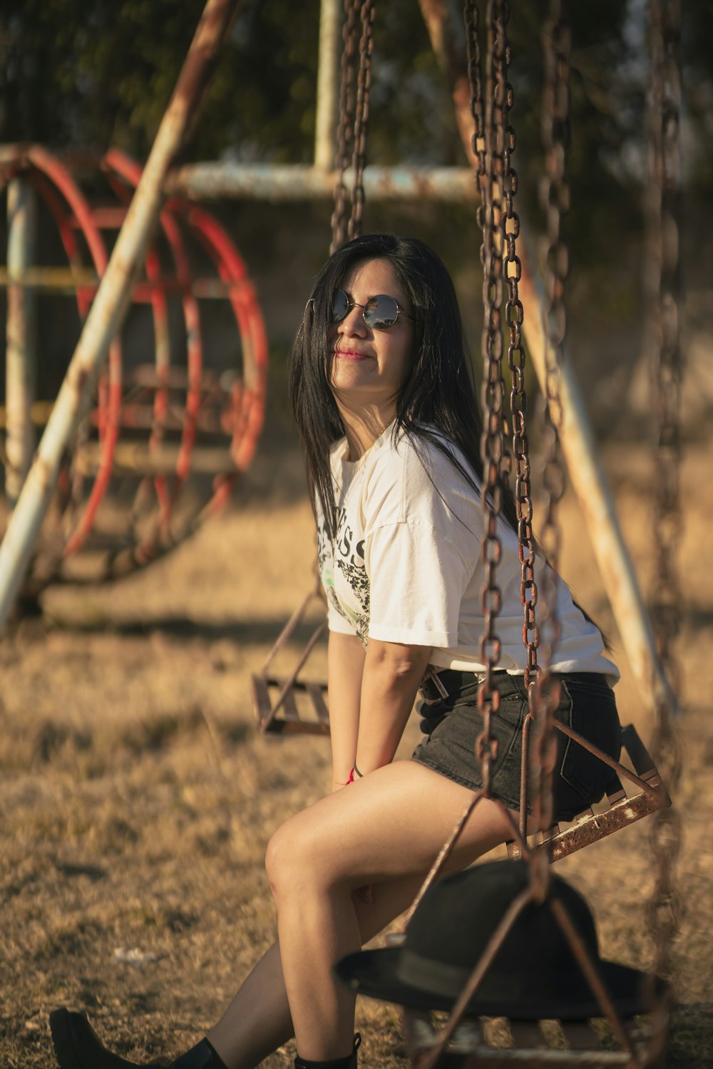 a woman sitting on a swing in a park