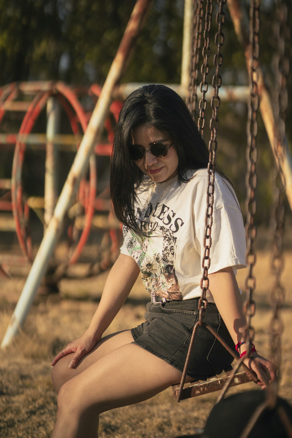 a woman sitting on a swing in a park