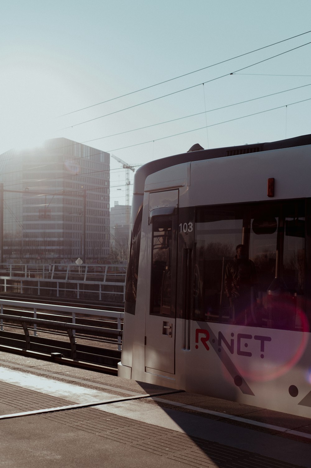 a white train traveling down train tracks next to tall buildings