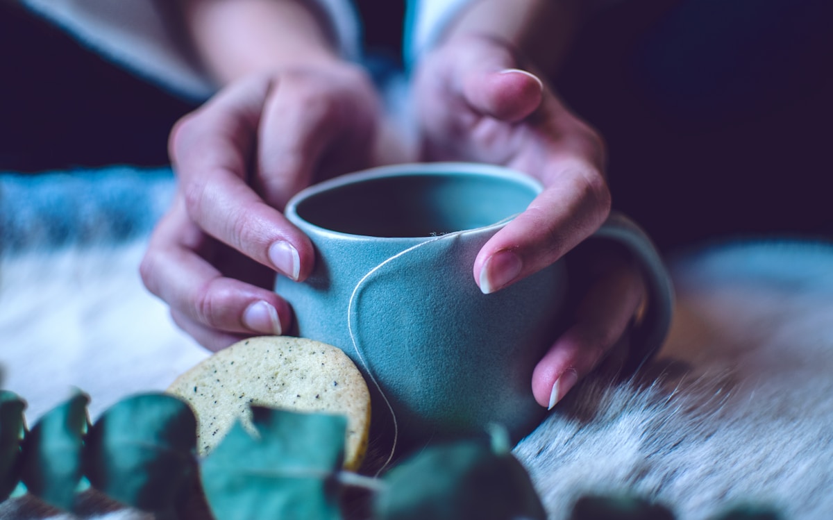a person holding a cup with a cookie on it
