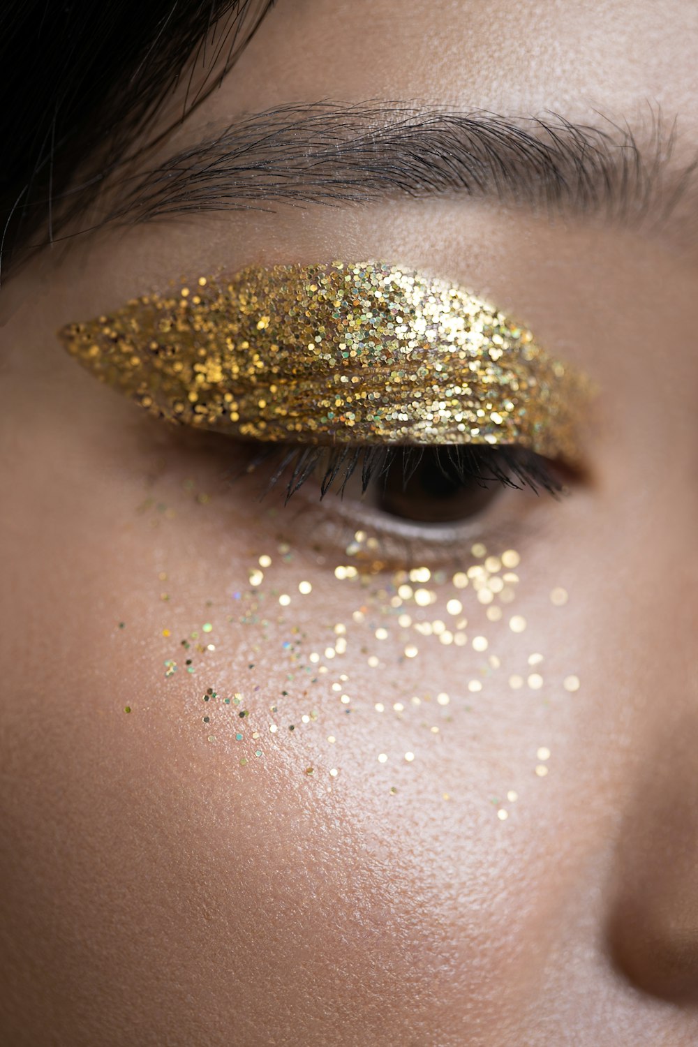 a woman with gold glitter on her eyes