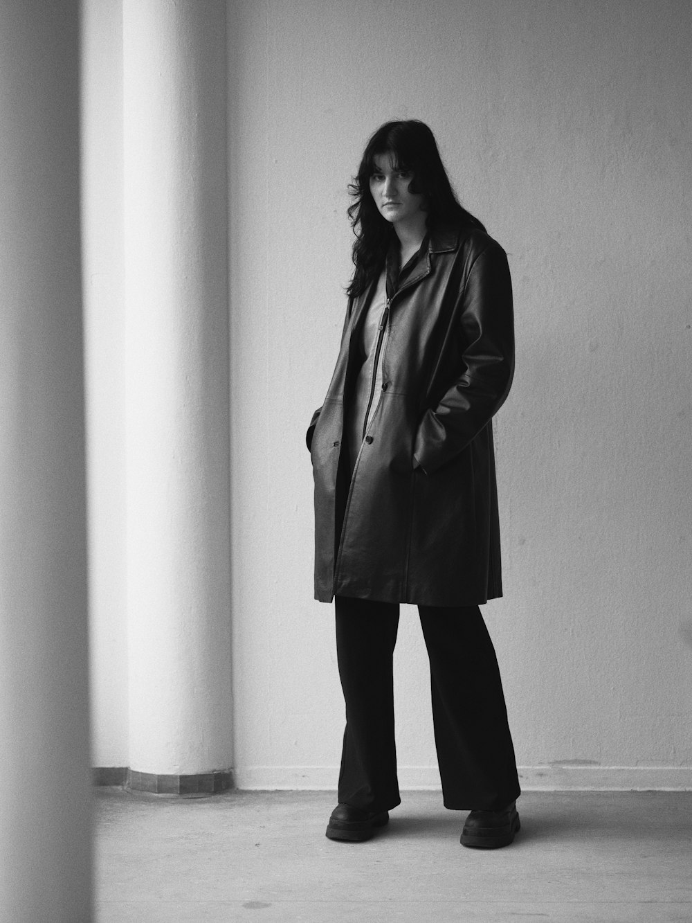 a woman standing in a room with a coat on