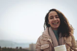 a woman holding a cup of coffee and smiling