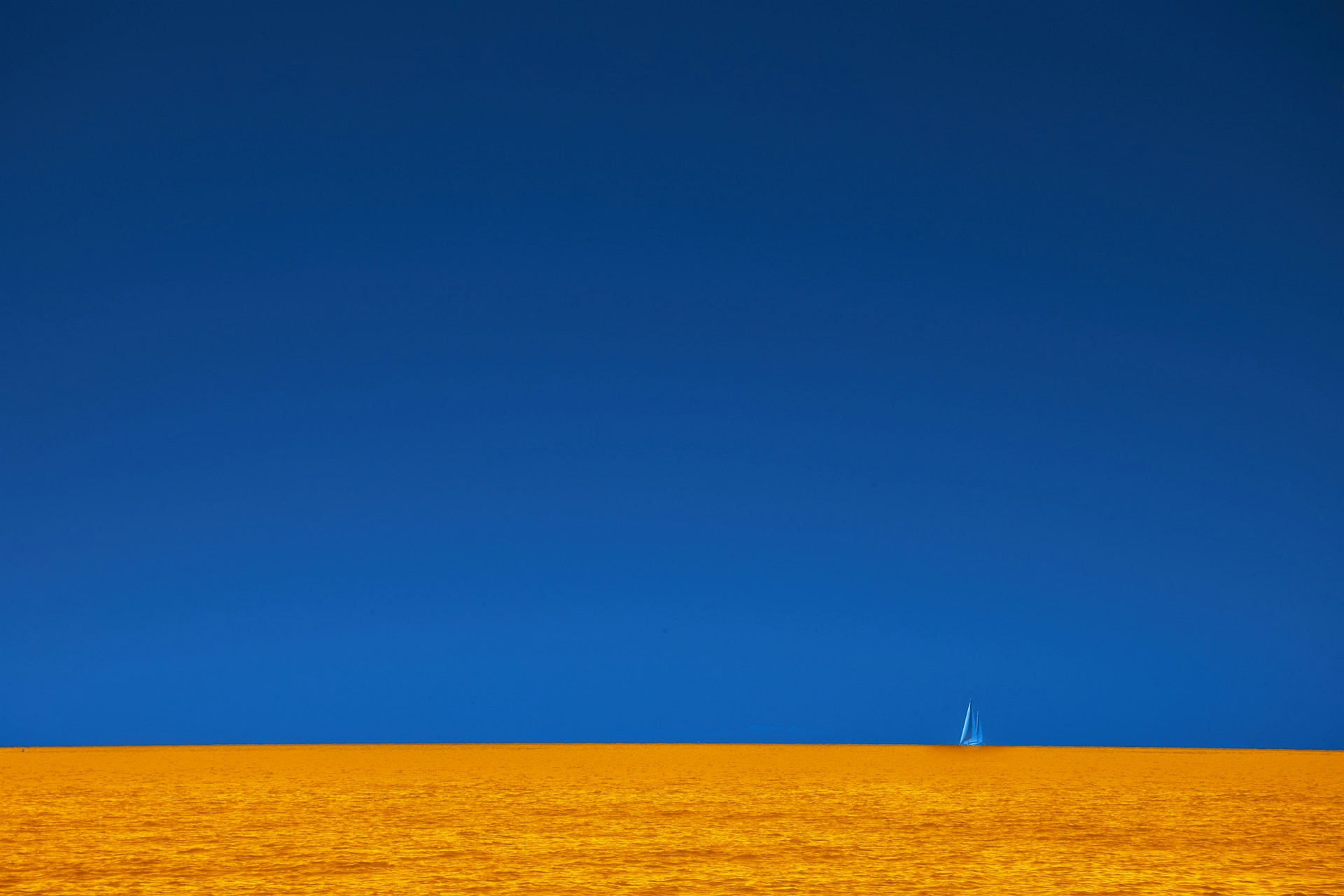 a lone sailboat in the distance on a clear day
