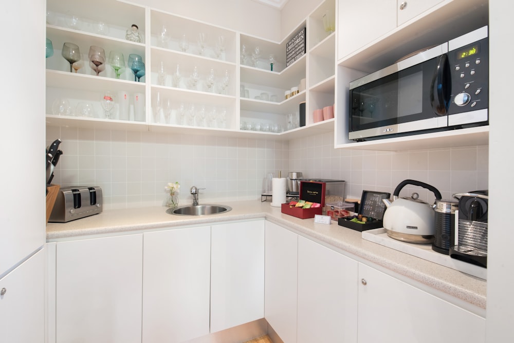 una cocina con armarios blancos y microondas