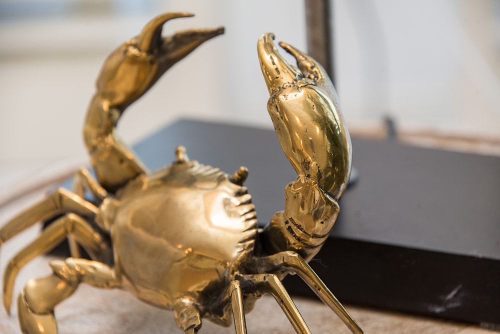 Una estatua de cangrejo dorado sentada encima de una mesa