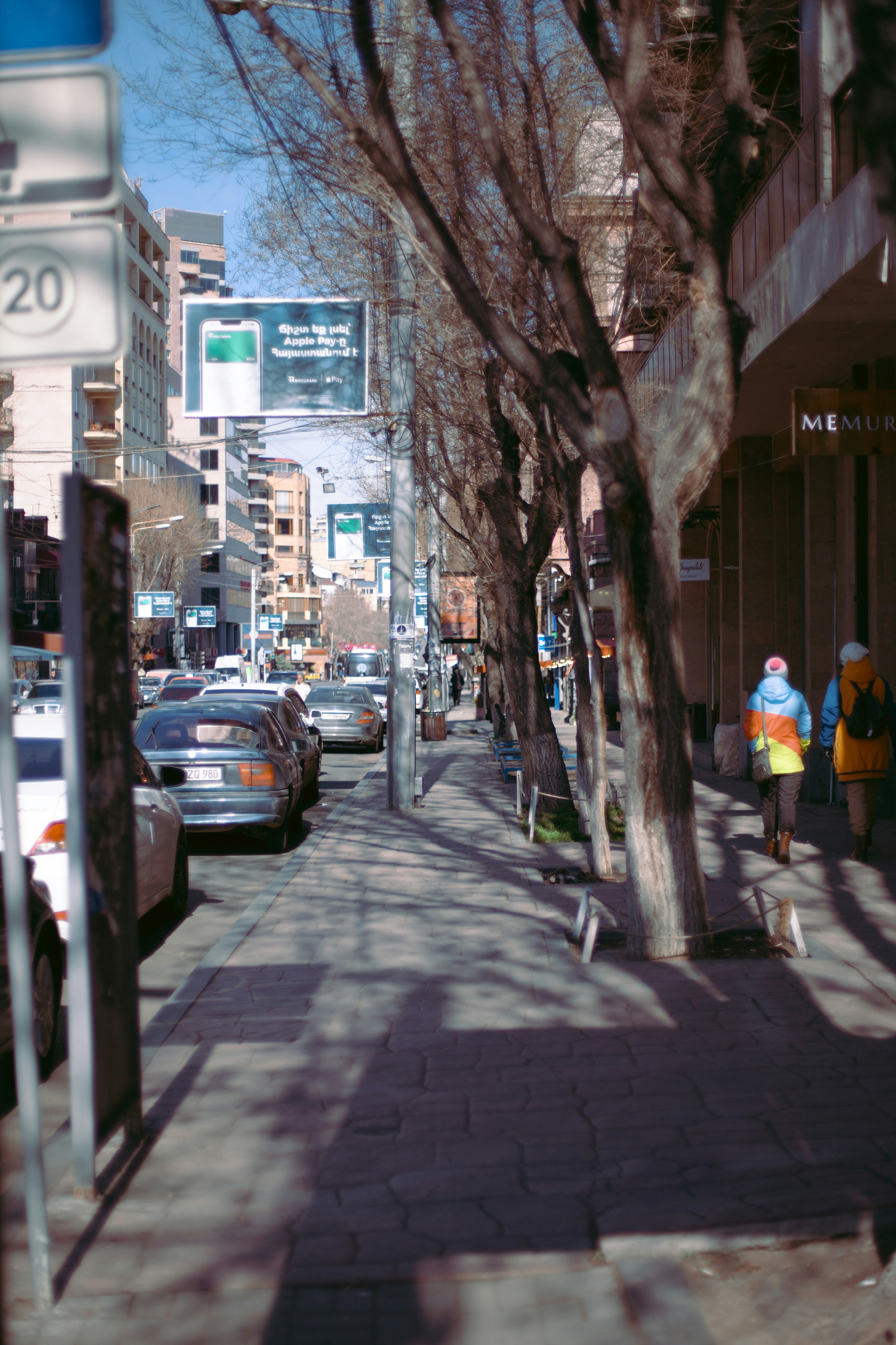 a city street lined with parked cars and tall buildings