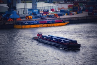 Trucks and barges coordinating coal transport at a bustling industrial port.