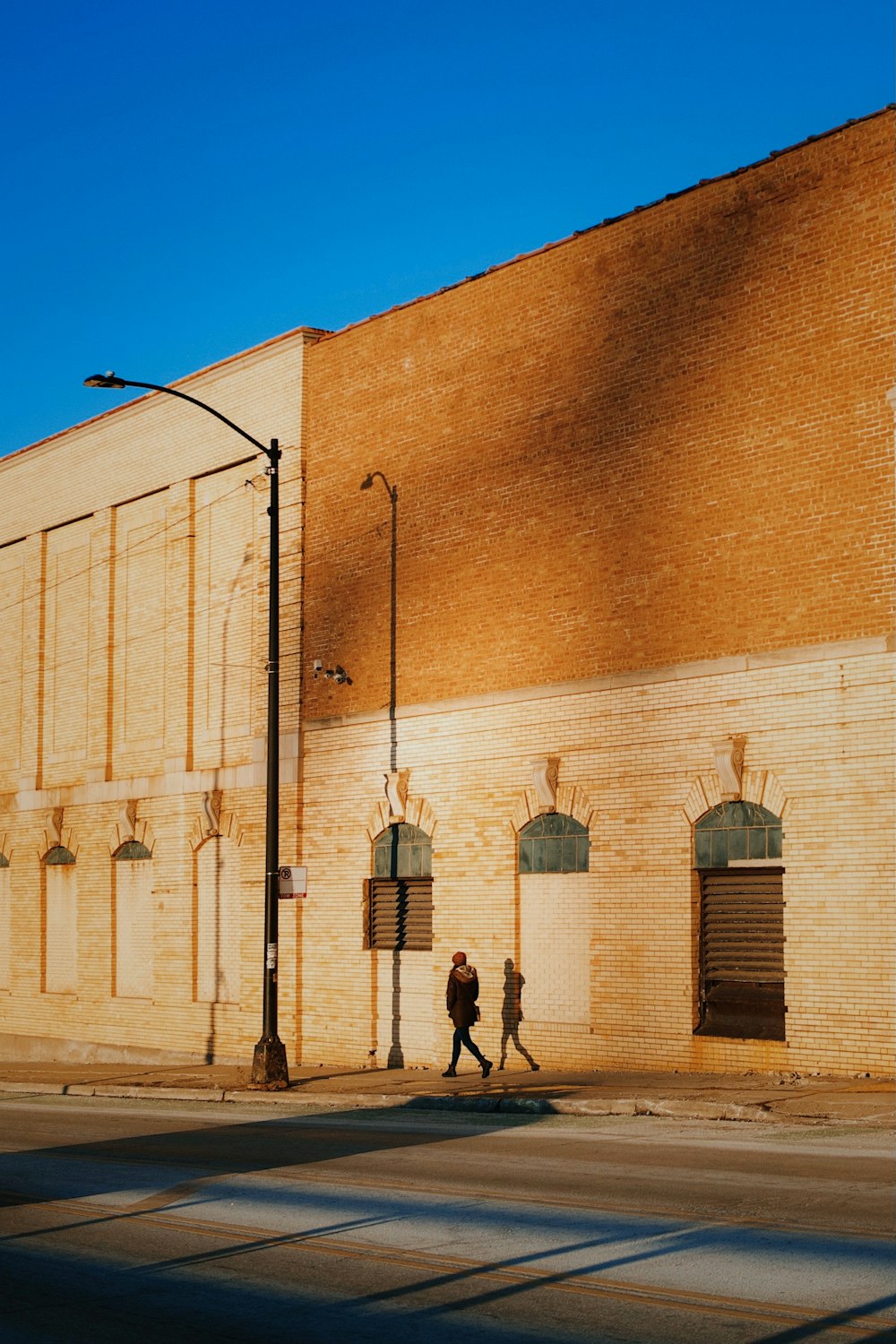 a couple of people walking down a street next to a tall building