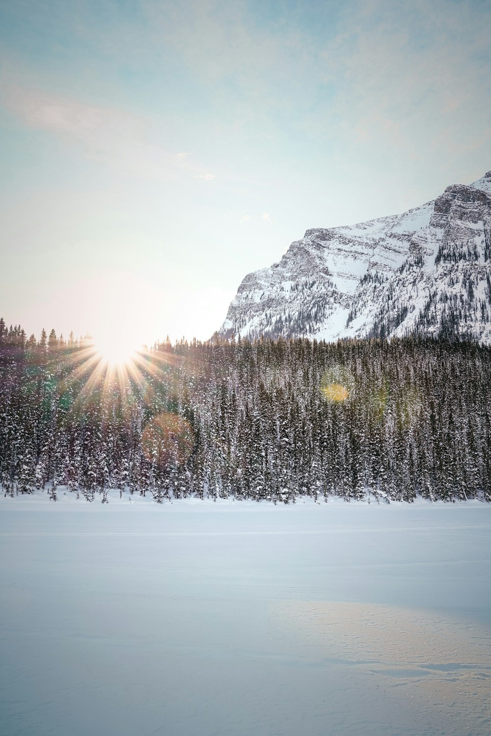 the sun shines brightly through the snow covered mountains