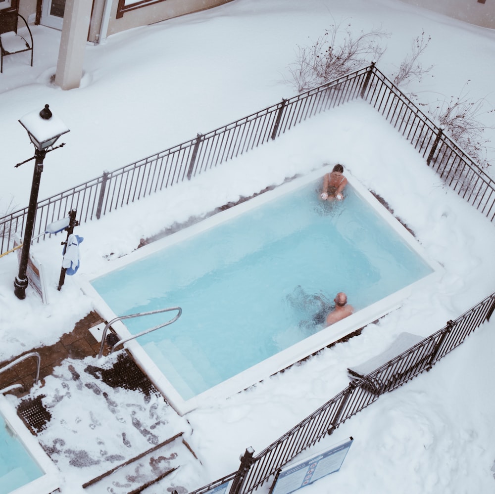 a couple of people in a swimming pool covered in snow