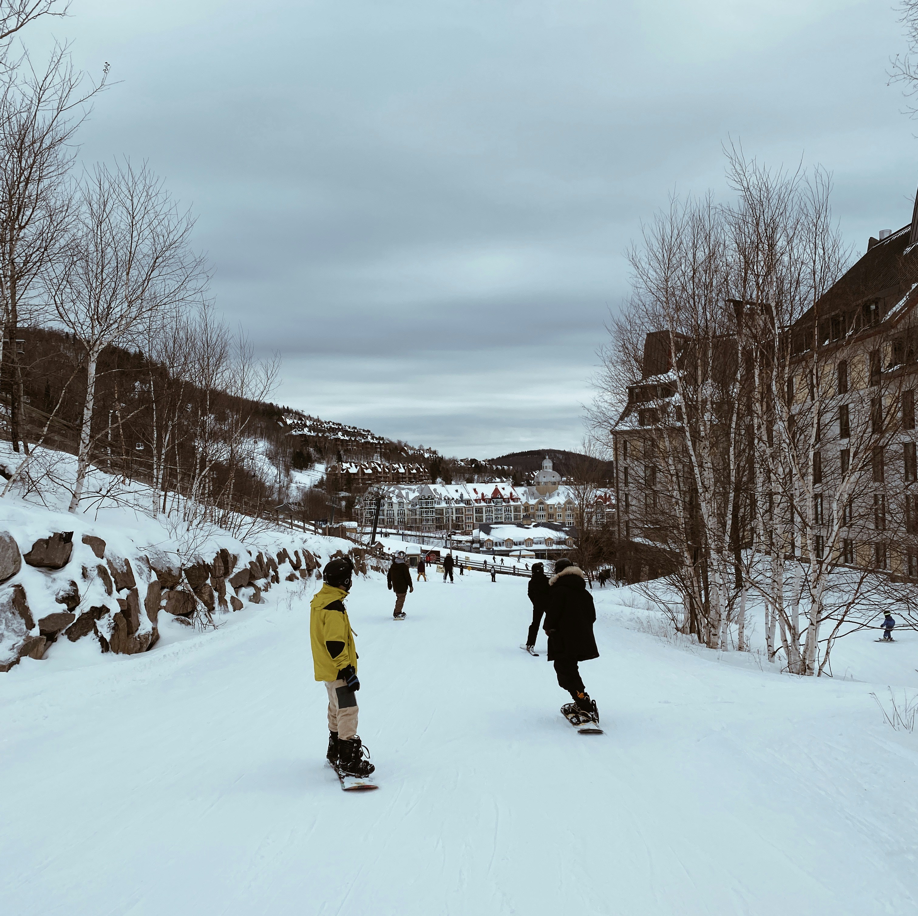 a group of people riding snowboards down a snow covered slope