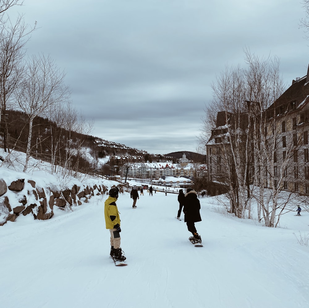 a group of people riding snowboards down a snow covered slope