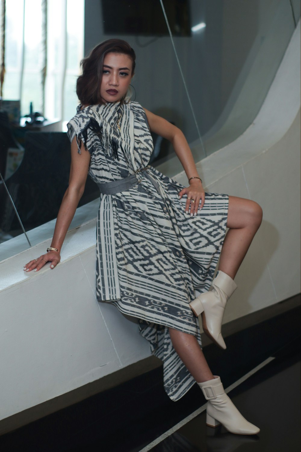 a woman in a dress leaning against a wall