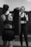 Two women are in a gym setting, with one holding a boxing pad while the other is positioned as if preparing to punch. Both are in athletic wear, focused and engaged in their activity. The environment appears to be a training room with padded flooring and walls.