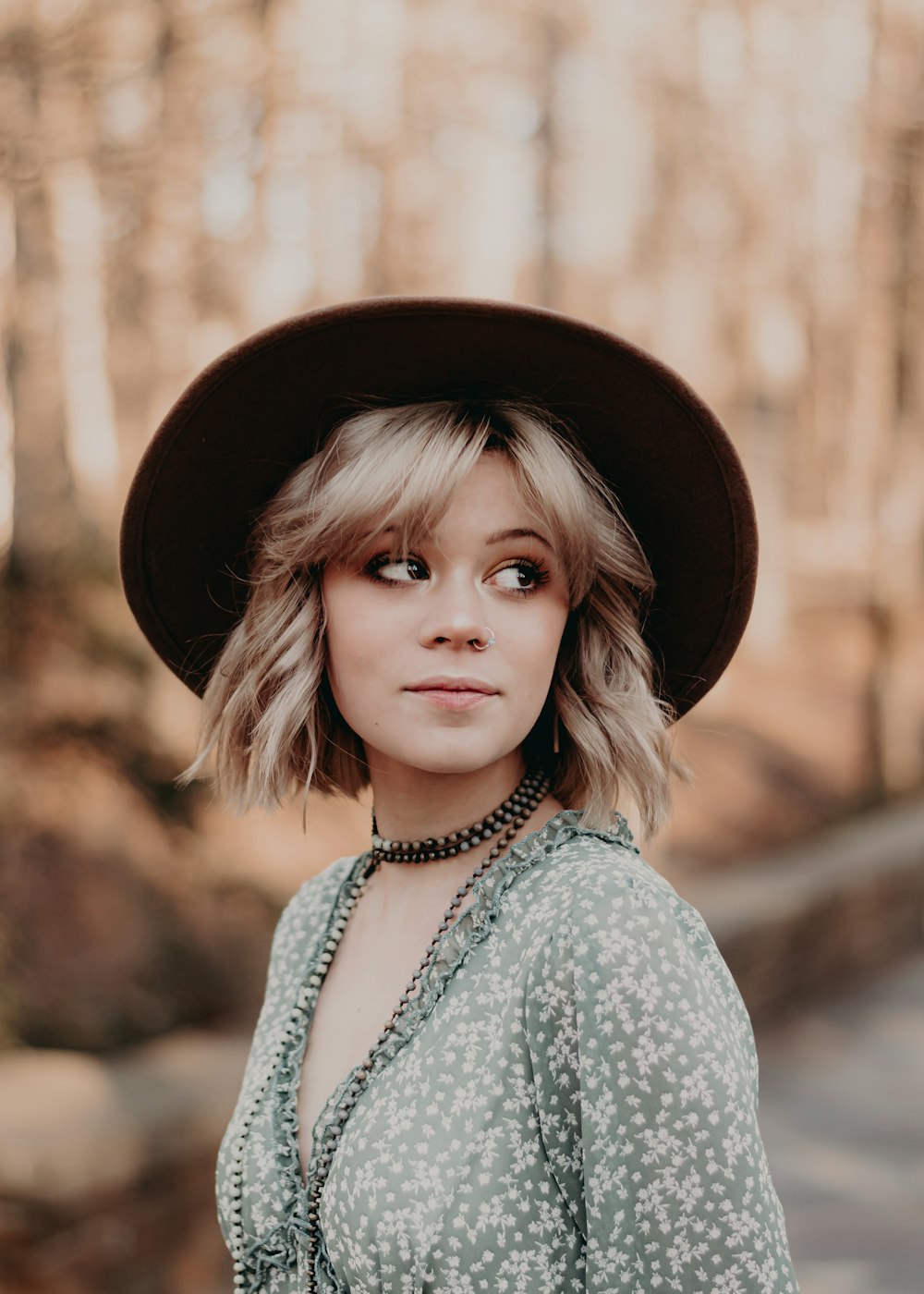 a woman wearing a hat standing in the woods