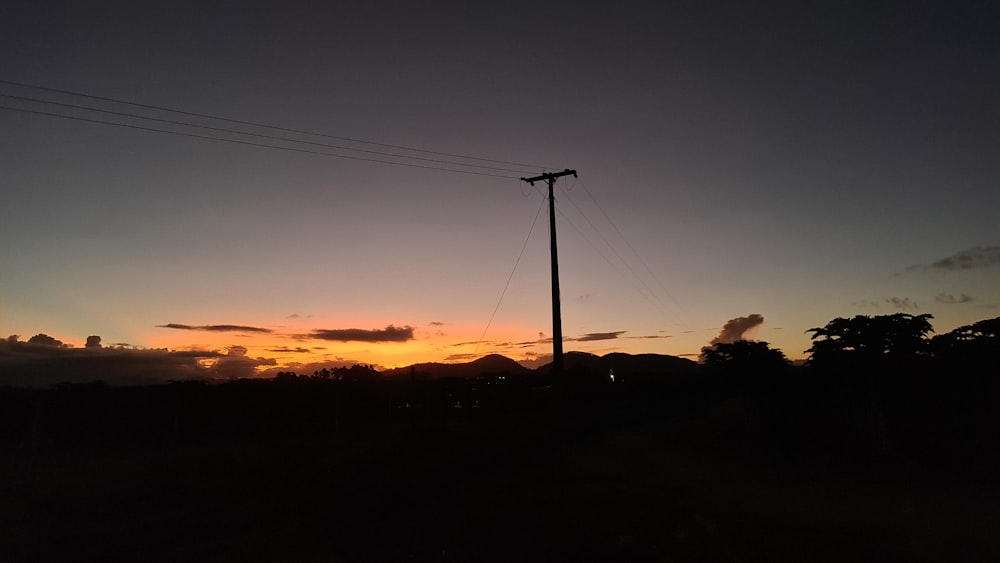 the sun is setting behind a telephone pole