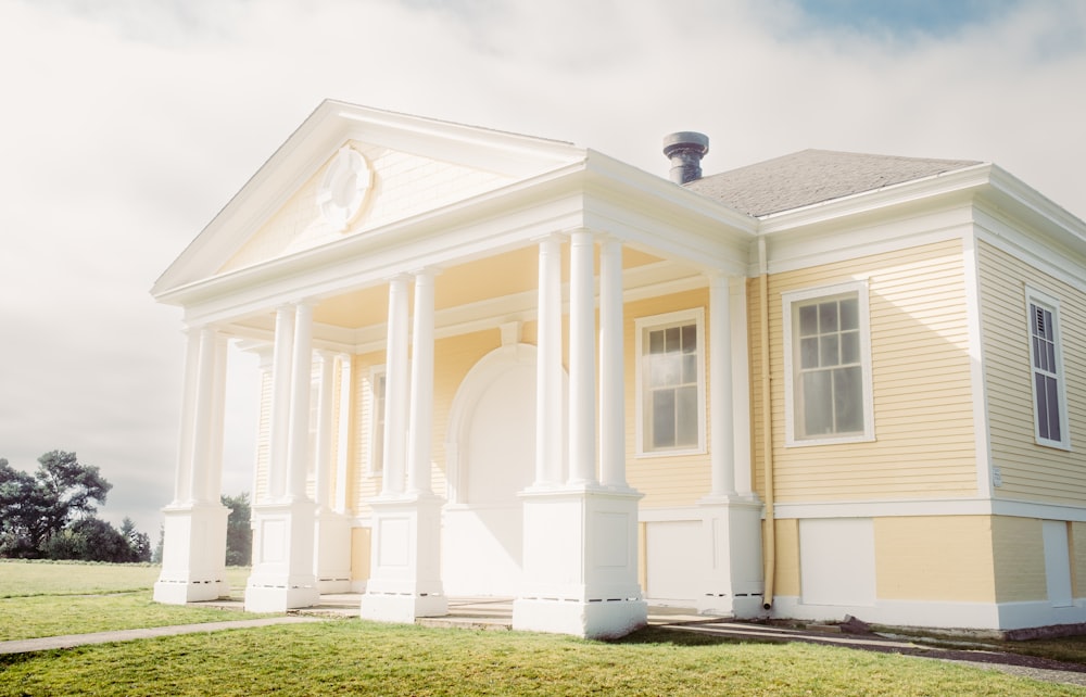 a white and yellow house with columns and a porch