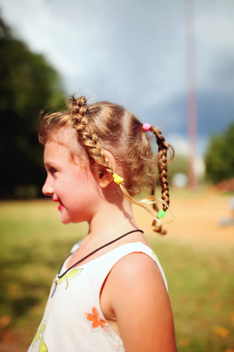 A young girl wearing her hair in two neat braids, photographed close up.