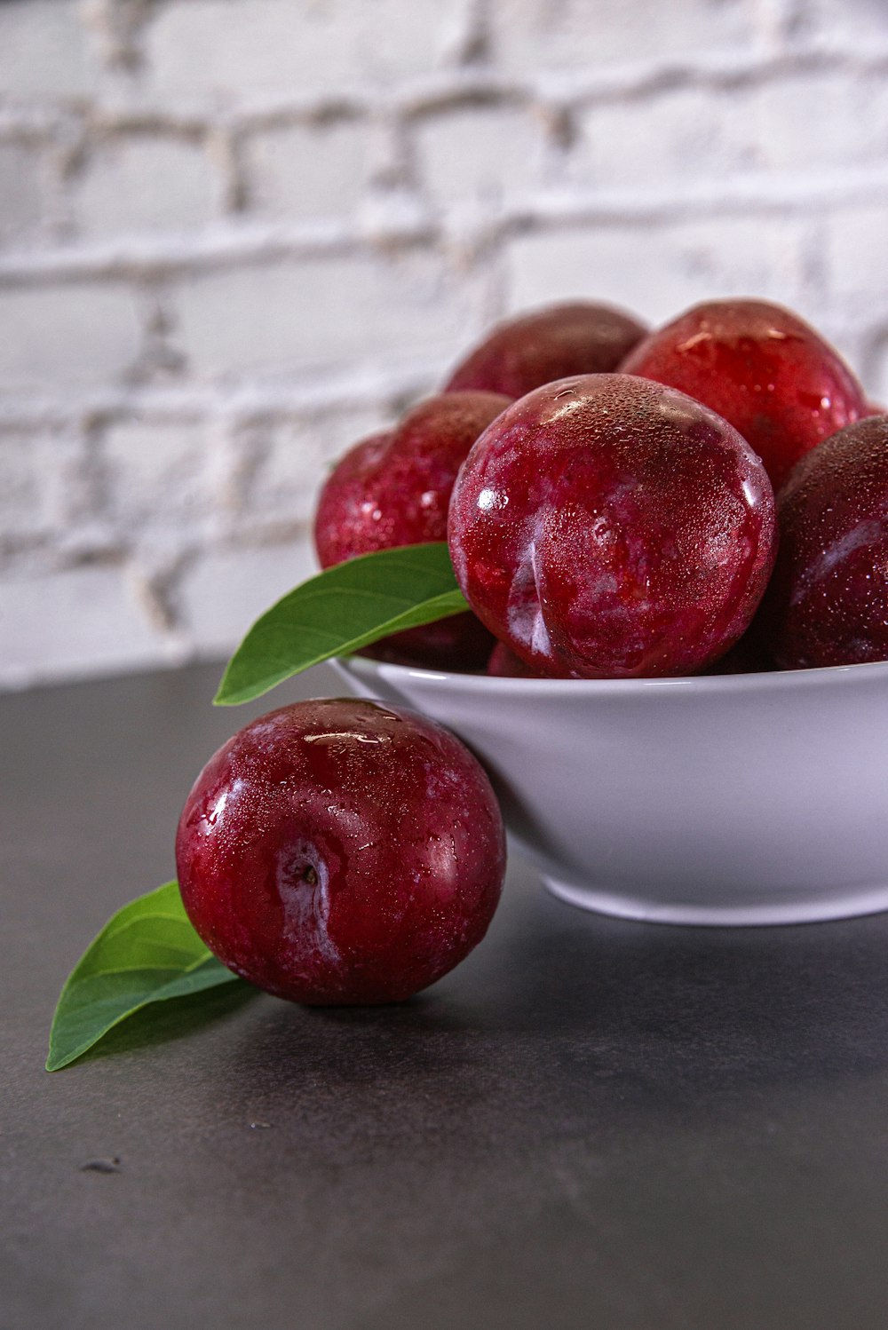 a white bowl filled with red apples on top of a table