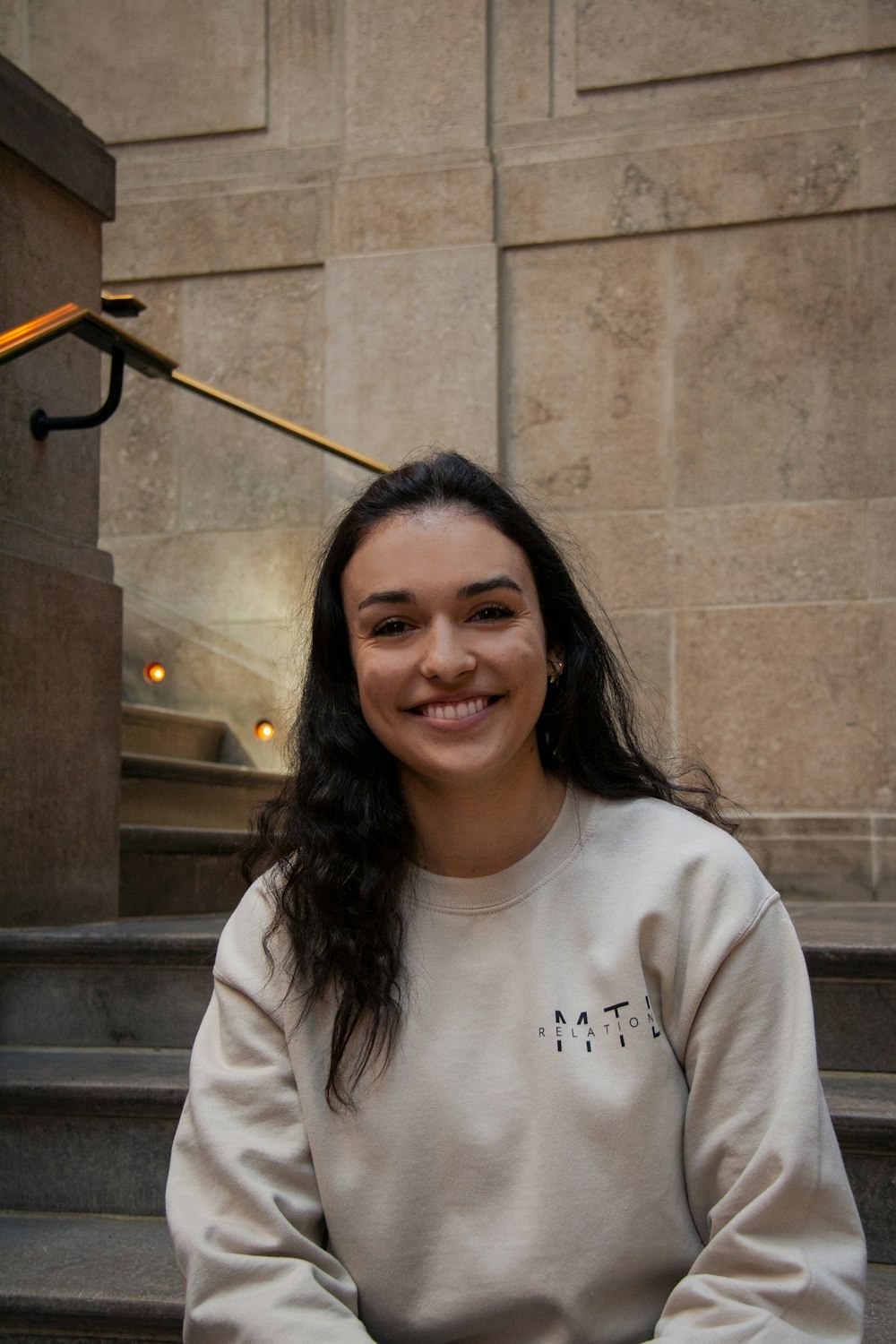 a smiling woman sitting on the steps of a building