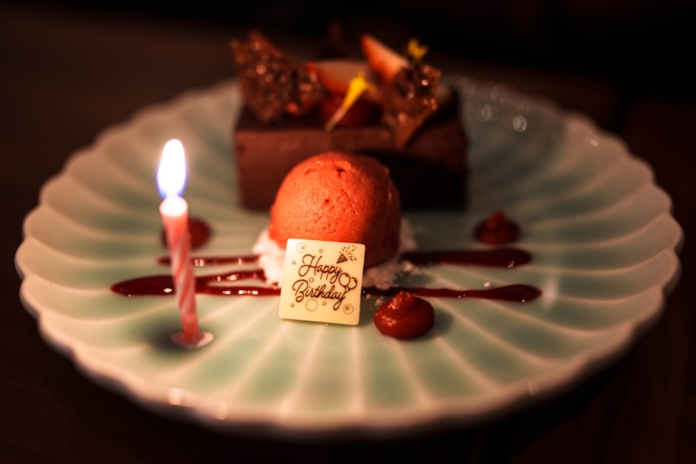 a white plate topped with a piece of cake and a candle