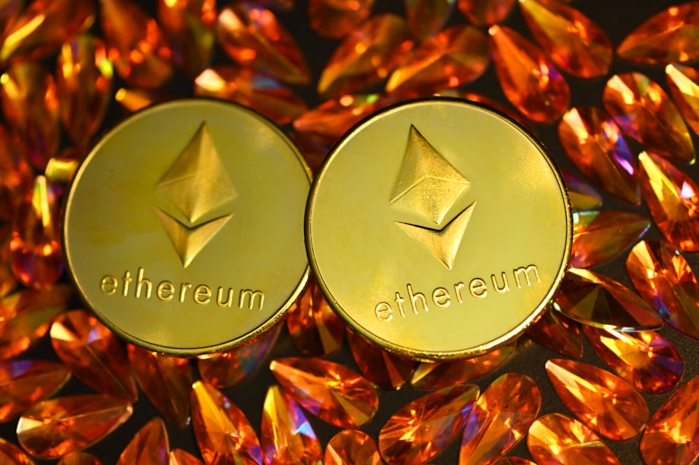 two gold ethereum tokens sitting on top of a pile of crystals