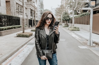 A stylish model checking her schedule on a sleek smartphone in a bustling city street.