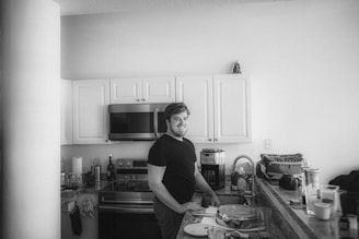 a man standing in a kitchen next to a counter