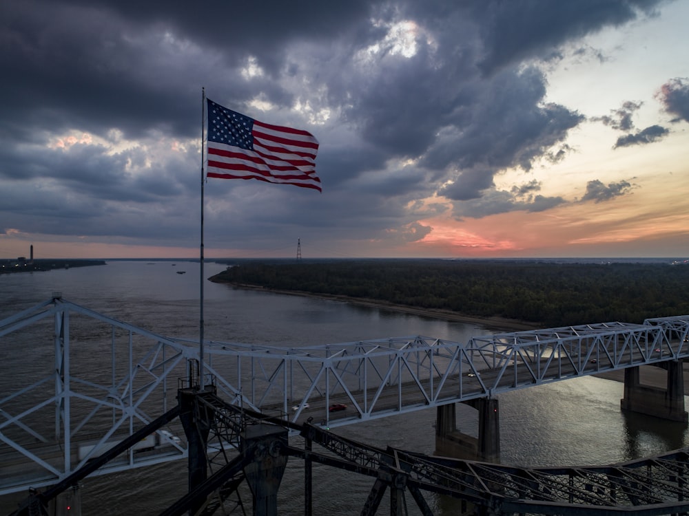 an american flag flying on a bridge over a body of water