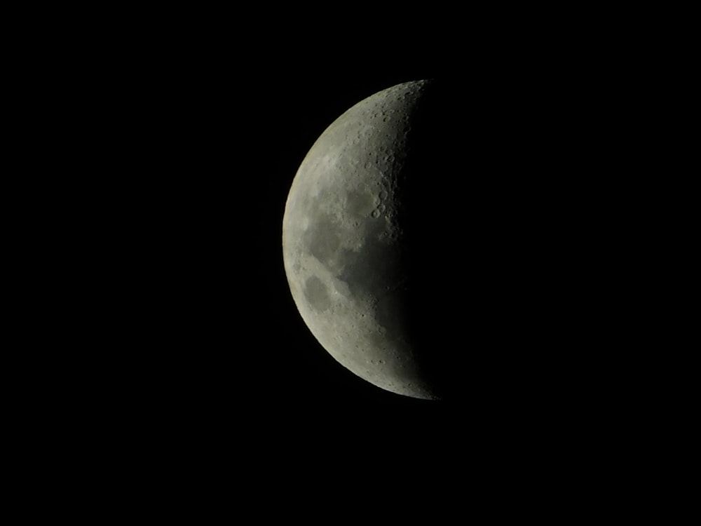 a half moon is seen in the dark sky