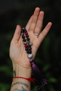 a woman's hand holding a rosary with a tassel