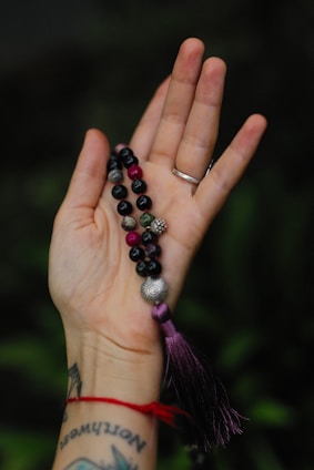 a woman's hand holding a rosary with a tassel