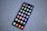 A smartphone with a large screen displaying various colorful app icons arranged in a grid. The smartphone is laying on a gray, speckled surface.