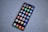 A smartphone with a large screen displaying various colorful app icons arranged in a grid. The smartphone is laying on a gray, speckled surface.