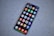 A smartphone with a large screen displaying various colorful app icons arranged in a grid. The smartphone is laying on a gray, speckled surface.