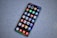 A smartphone with a large screen displaying various colorful app icons arranged in a grid. The smartphone is laying on a gray, speckled surface.