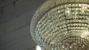 A close-up of a crystal chandelier casting soft light over a sleek marble dining table set with fine china.