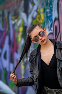 Street-style shot of a person sporting a sleek black leather beret against an urban graffiti wall.