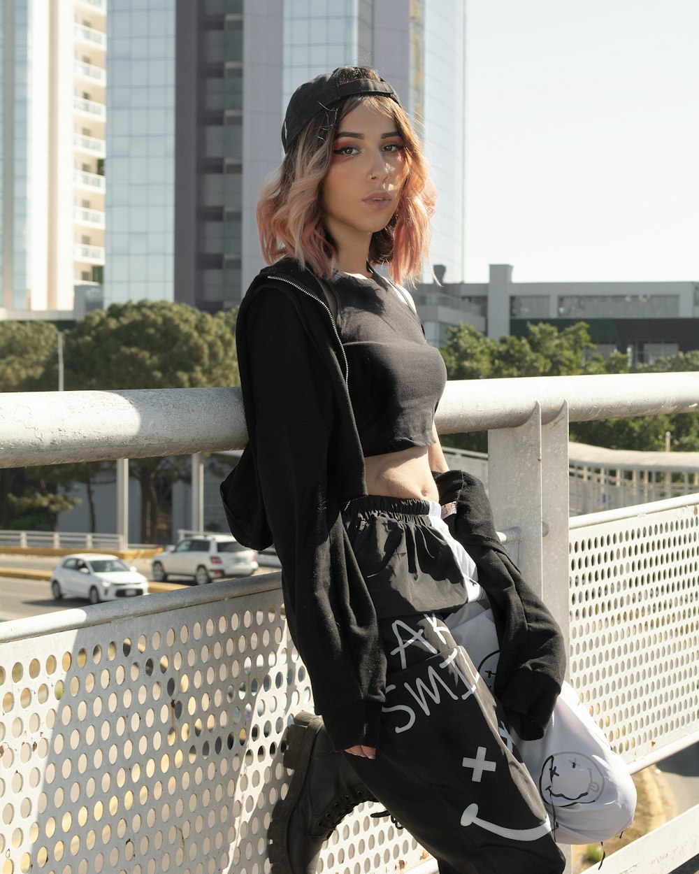 a woman with pink hair is standing on a bridge
